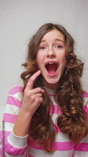 Vertical video little girl feeling hungry and pointing at mouth