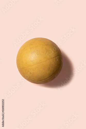 Weighted yellow exercise ball on a pink background photo