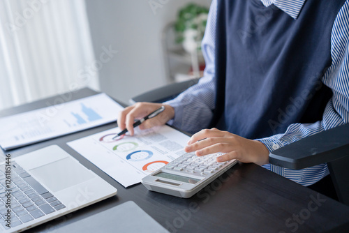 Asian businesswoman doing paper work with pen laptop calculator photo