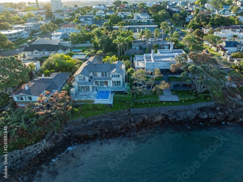 Coastal luxury homes with a modern pool, nestled along the waterfront. Aerial view of a beautiful residential neighborhood. TAKAPUNA, AUCKLAND, NZ photo