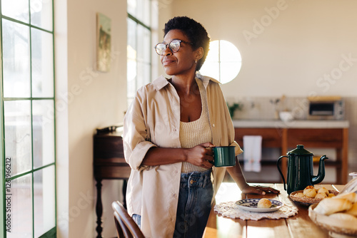 Foto Thoughtful black woman enjoying her morning with fresh coffee and cheese bread r