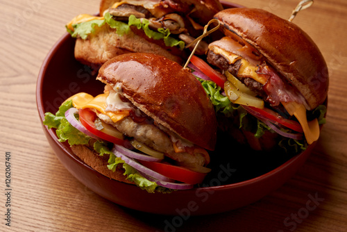 A close-up of three burgers, showcasing the juicy patty, crispy bacon, and soft bun. The burgers are filled with fresh toppings and served on a sesame seed bun. photo