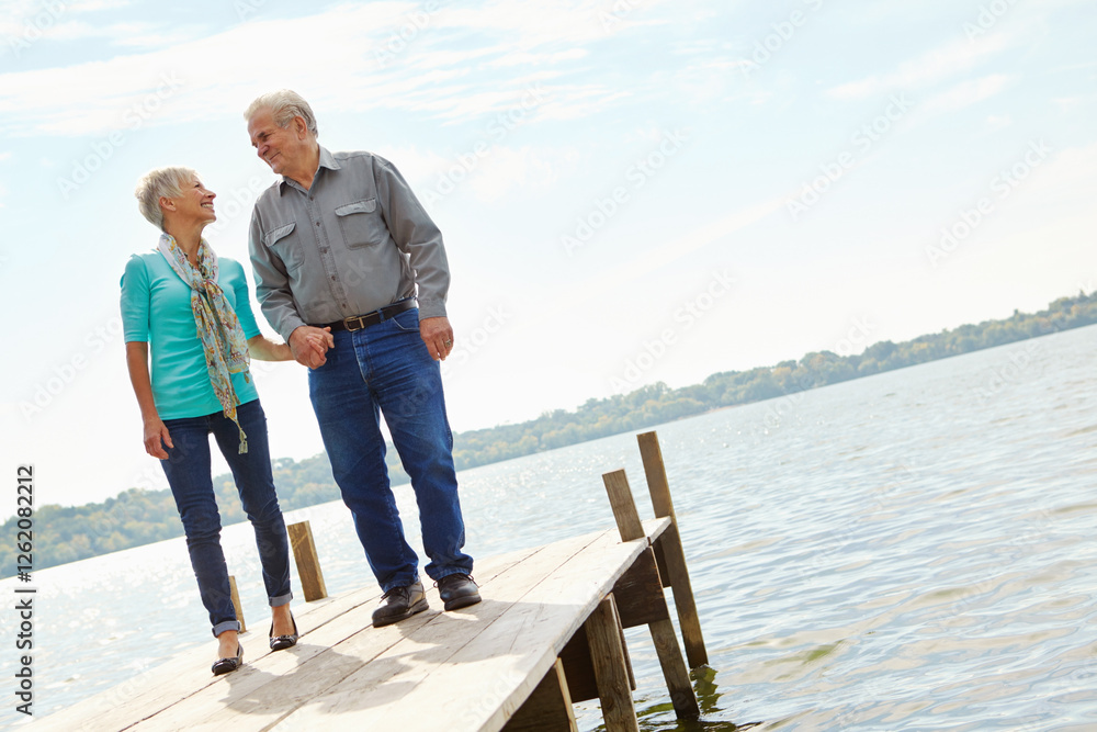 Fototapeta premium Happy, senior and couple walking on pier for retirement, vacation journey and travel destination. Below, elderly people and holding hands for marriage commitment, holiday location and bonding on lake