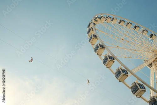 Tourists ziplining over ferris wheel on sunny day photo