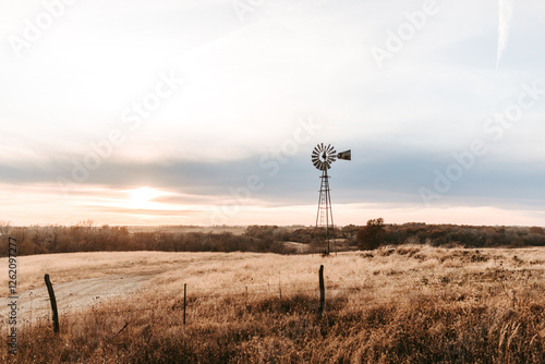 Windmill in a golden Kansas field at sunset with a wide, open sky. photo