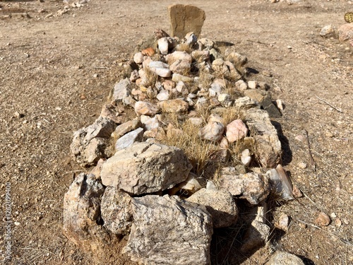 Close-up of a rustic desert grave marked by piled stones and dirt photo