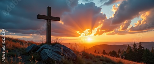 Dramatic Easter Sunset Scene: Wooden Cross on Hilltop amidst Nature's Palette. A wooden cross sits atop a grassy hill under a dramatic sunset. photo