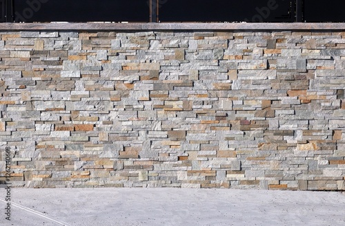 Wallpaper Mural Fence made of faux stone veneer wall and black metal paneling on top . Concrete flooring. Background and texture.  Torontodigital.ca