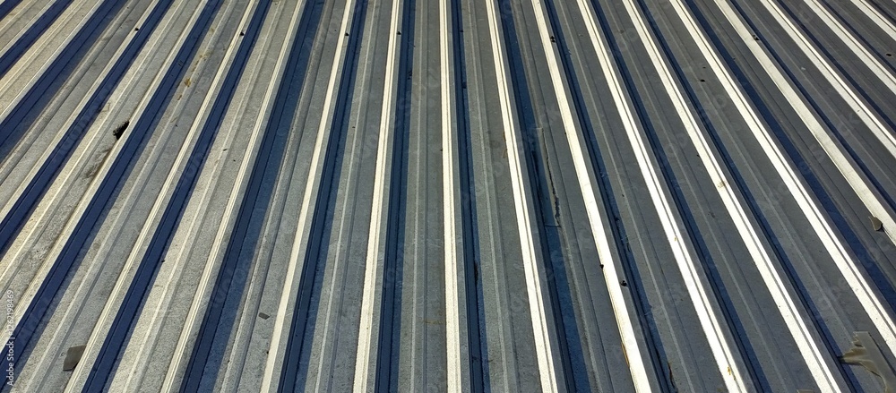 Fototapeta premium Close-up view of a textured metal surface showing parallel lines and shadows, conveying industrial aesthetics and modern design