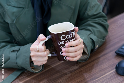 A young woman's hands' holding a coffee mug implying peace, warmth and breaktime.  photo