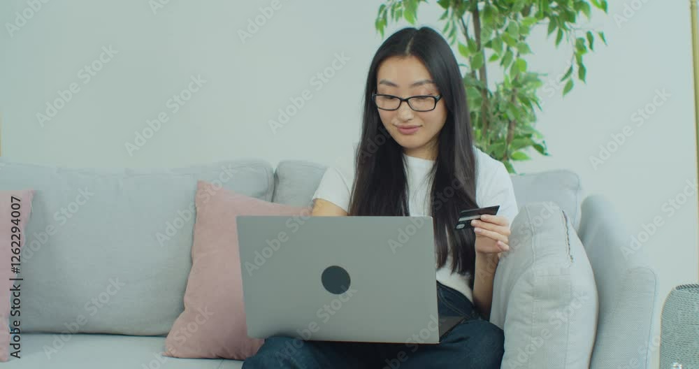 Attractive woman is entering credit card number for online shopping using laptop computer sitting at home communication technology banking money finance browsing paying slow motion. Attractive woman is entering credit card number for online shopping using laptop computer sitting at home communication technology banking money finance browsing paying slow motion.