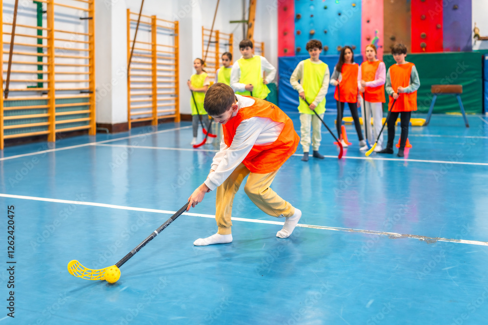 Fototapeta premium Students playing floorball in gym class at school