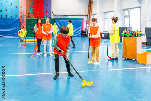 Students playing floorball in school gym during physical education class photo