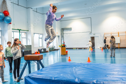 Slika na platnu Young girl performing gymnastics vaulting in school gym class