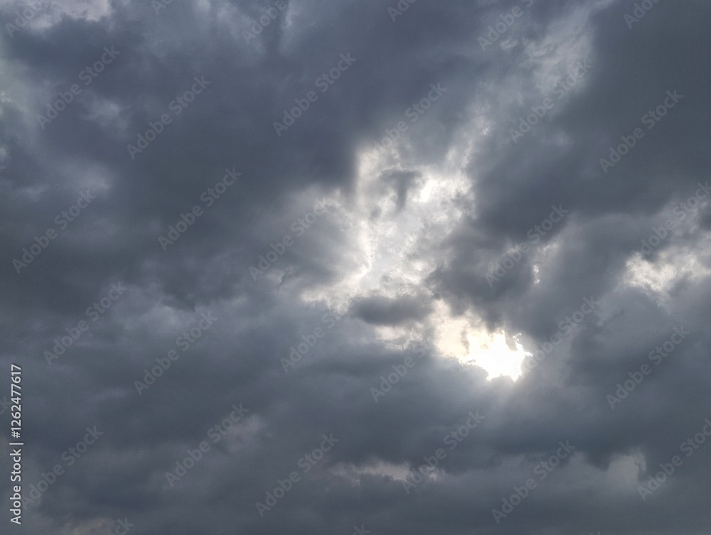 Dramatic dark clouds with sun shining behind, Natural texture background Dramatic dark clouds with sun shining behind, Natural texture background