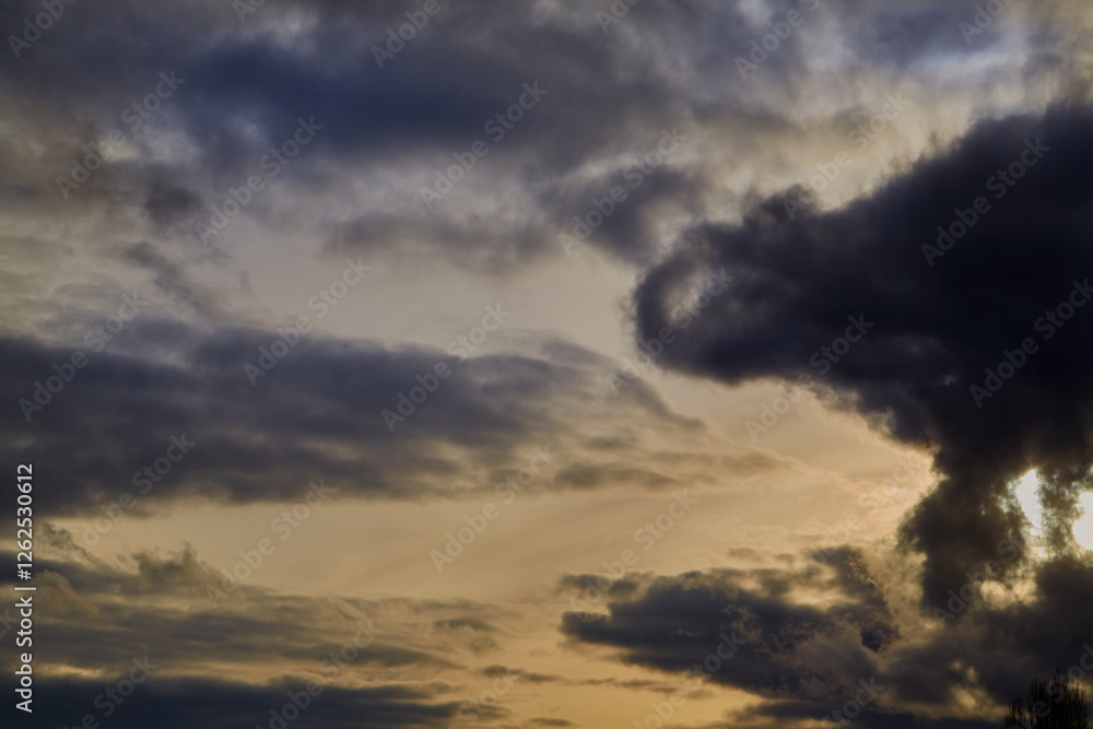 Fototapeta premium Layered clouds in the sky form voluminous shapes, creating a dramatic effect. Sunlight gently diffuses across their surface, adding shades of blue and gray.