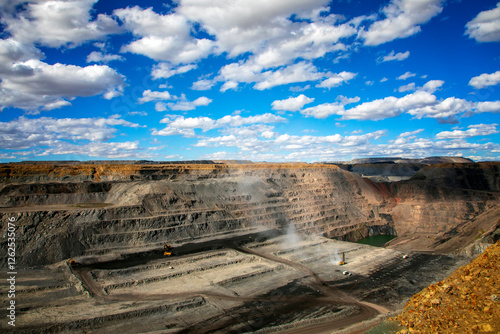 Massive mining trucks and excavators operate in a coal and copper mine, showcasing industrial power and resource extraction. A dramatic view of modern mining technology at work