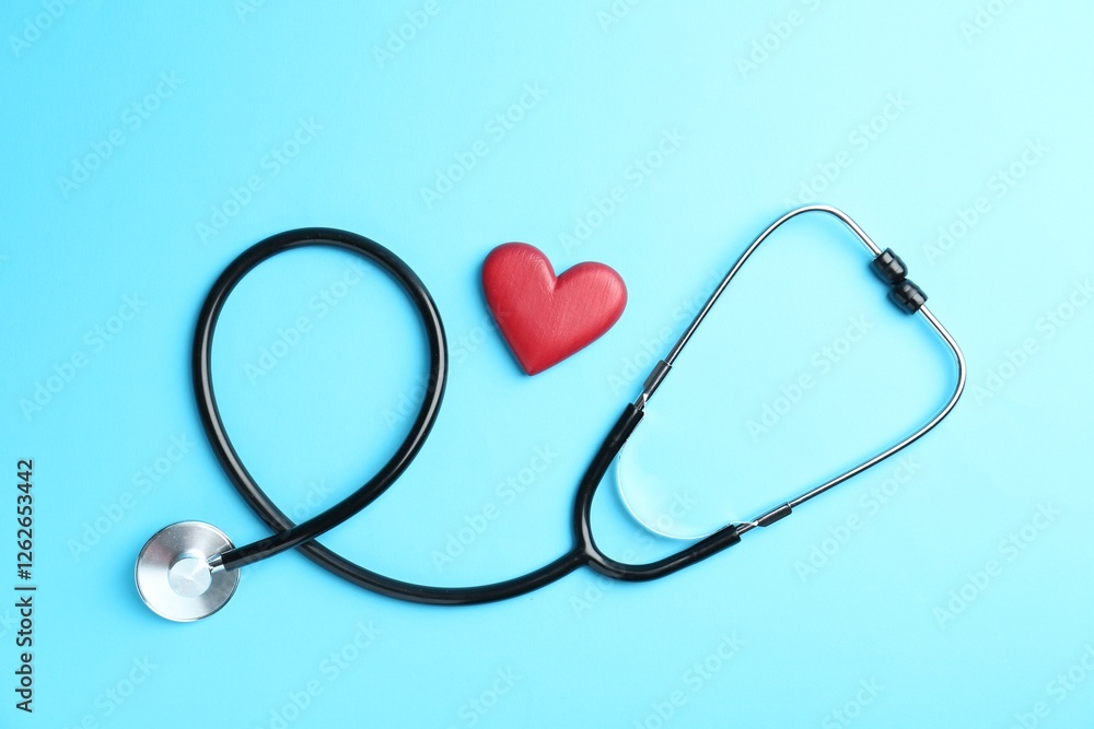Cardiology. Stethoscope and red decorative heart on light blue background, flat lay Cardiology. Stethoscope and red decorative heart on light blue background, flat lay