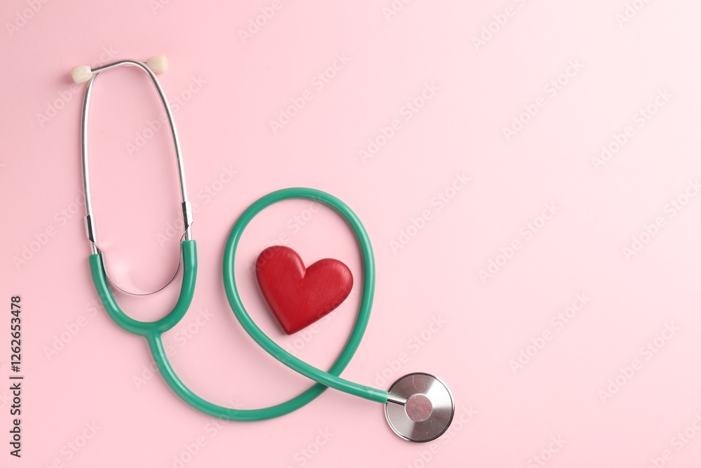Fototapeta premium Cardiology. Stethoscope and red decorative heart on pale pink background, flat lay. Space for text