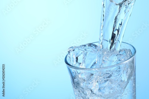 Pouring refreshing soda water into glass on light blue background, closeup. Space for text