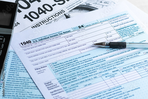 Blank color print paper Form 1040 U.S. Individual Income Tax Return 2024. With a black ball pen and calculator. Taxation, tax season 2025, tax payment, regulatory filing, personal finance concept