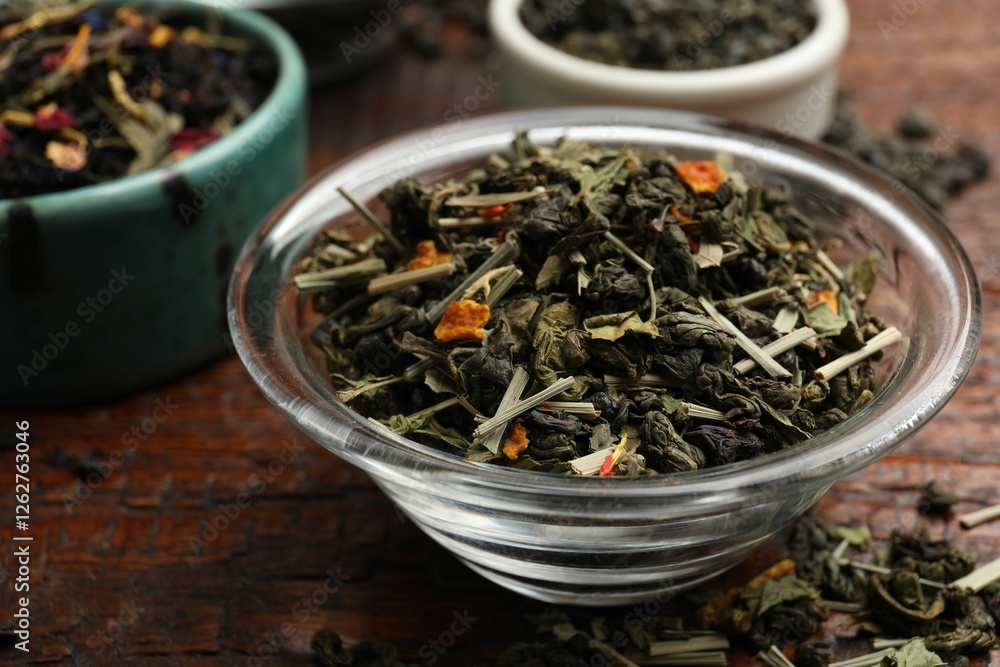 Different dry tea leaves in bowl on wooden table, closeup Different dry tea leaves in bowl on wooden table, closeup
