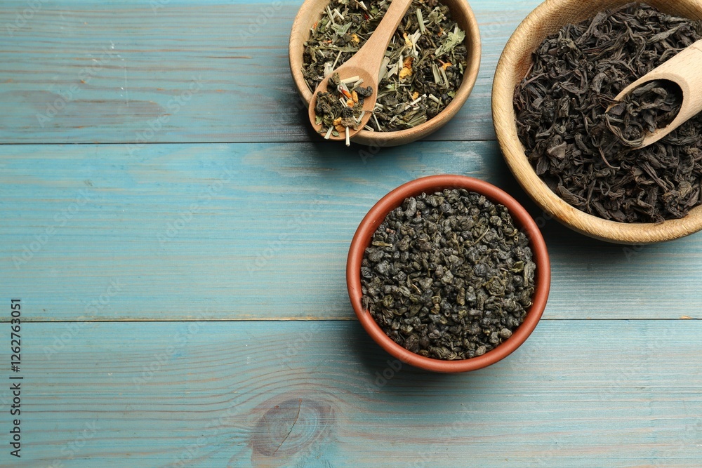 Different dry tea leaves in bowls on light blue wooden table, flat lay. Space for text Different dry tea leaves in bowls on light blue wooden table, flat lay. Space for text