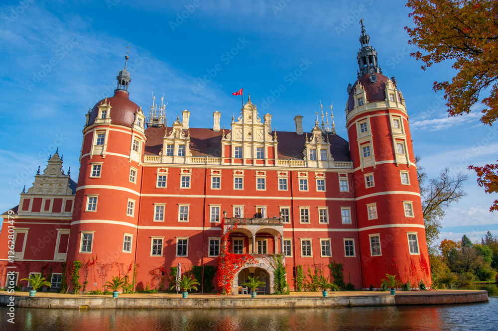 Fototapeta premium Schloss Muskau, Muskau palace, Saxony, Germany. UNESCO World Heritage Site. Autumnal landscape at the Prince Pückler Park, Bad Muskau. Palace on the lake. Reflection in water
