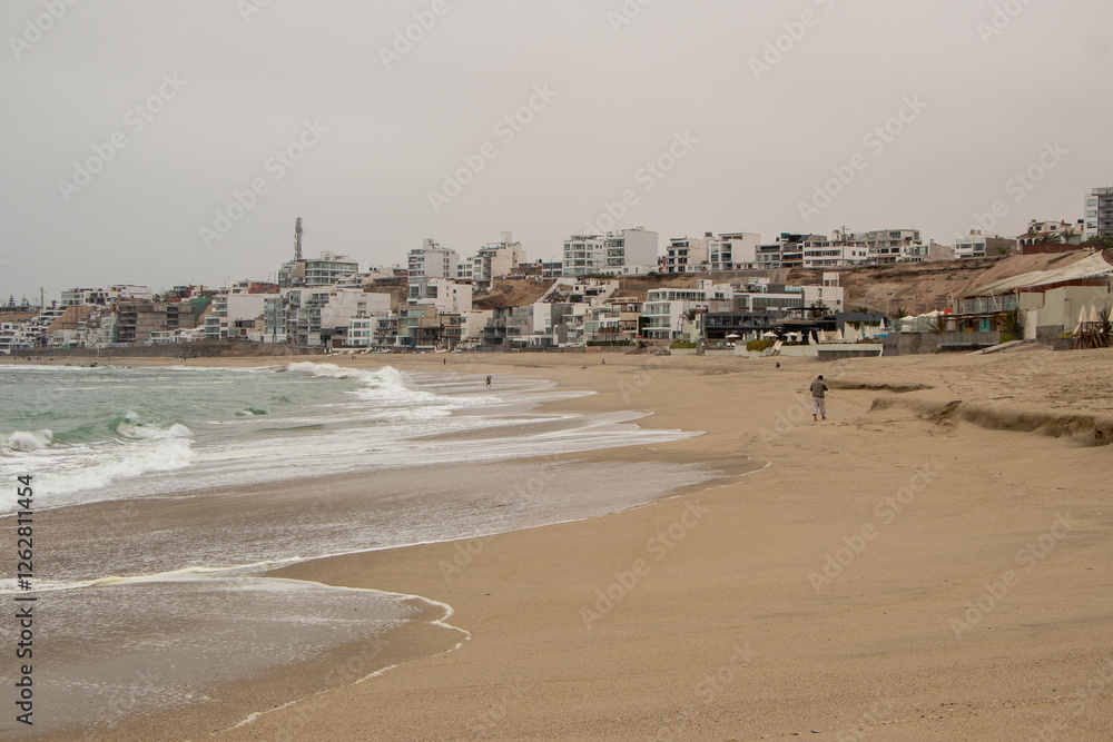 sandy beach with waves with buildings in the background in punta hermosa Perú 