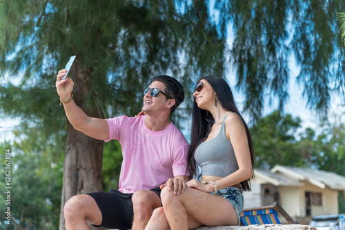 Obraz na płótnie Young Lover Man take vdo call with woman they are very happy and smile in outdoor background enjoy at the beach - summer vacation on sea beach concept w salonie