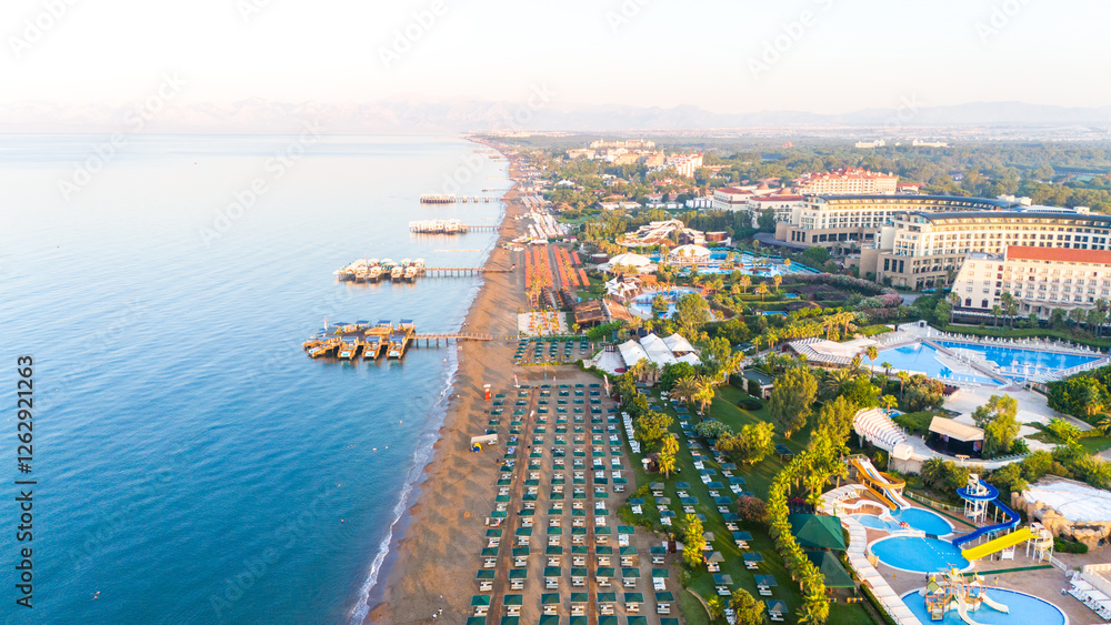 Fototapeta premium Aerial view of a luxury beachfront resort with private piers, pools, and a scenic coastline