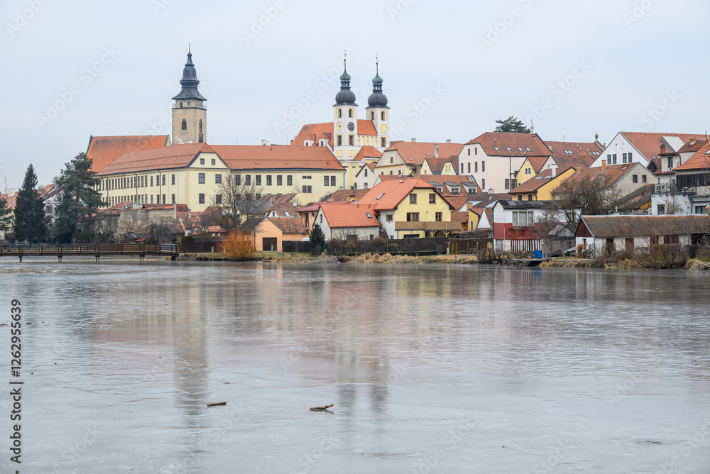 Obraz premium View of Historic old town of Telc, Unesco World Heritage Site, across frozen Ulicky rybnik pond in winter in Czech Republic
