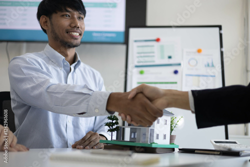 Wallpaper Mural A group of people are sitting around a table with a model house in the middle. They are all smiling and seem to be enjoying themselves
 Torontodigital.ca