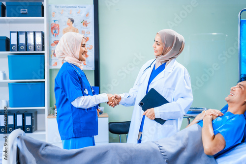 Asian middle-aged man patient rests in a hospital bed while a middle-aged Muslim woman doctor and a middle-aged Asian woman nurse check for diseases like flu and pneumonia, ensuring his recovery. photo