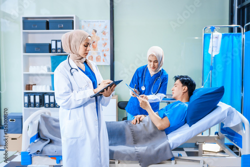 Asian middle-aged man patient rests in a hospital bed while a middle-aged Muslim woman doctor and a middle-aged Asian woman nurse check for diseases like flu and pneumonia, ensuring his recovery. photo