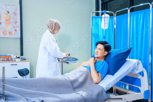 Asian middle-aged man patient rests in a hospital bed while a middle-aged Muslim woman doctor and a middle-aged Asian woman nurse check for diseases like flu and pneumonia, ensuring his recovery. photo