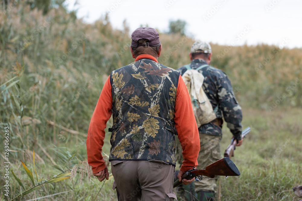Mature hunter man holding a shotgun and walking through a field Mature hunter man holding a shotgun and walking through a field
