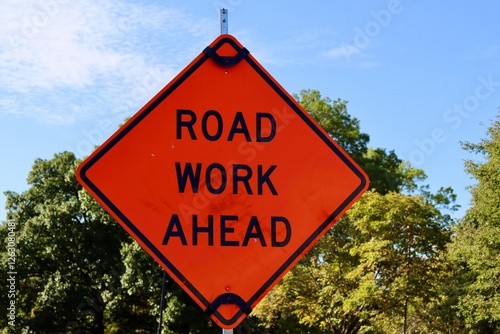 A close view of the orange road work ahead sign.