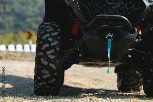 A close-up view of an all-terrain vehicle's rugged tires and winch, showcasing durability and off-road capability against a scenic backdrop. photo