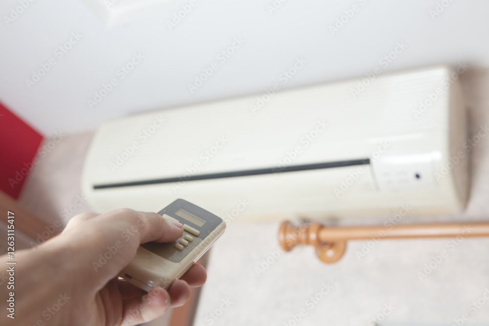 hand of woman holding air conditioner in the room