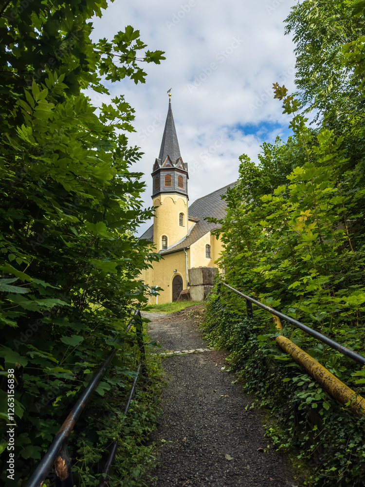 Naklejka premium Small castle nestled in picturesque German countryside. Historic architecture surrounded by lush greenery creates fairy tale atmosphere. 