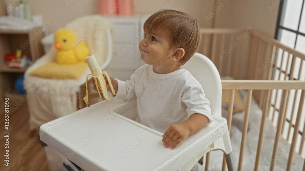 Smiling toddler holding a banana in a high chair indoors, surrounded by cozy nursery decor, exuding warmth and charm. Smiling toddler holding a banana in a high chair indoors, surrounded by cozy nursery decor, exuding warmth and charm.