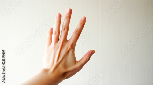 close-up of a fair-skinned hand with fingers spread open against a neutral background. photo