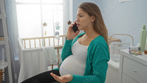 Obraz na płótnie Pregnant woman talking on phone in cozy bedroom with baby cradle, surrounded by gentle light creating a serene atmosphere in a home environment. w salonie