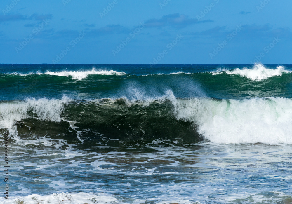 Ocean waves crashing on the shore under a blue sky, with the turquoise water rippling and splashing at Lumahai Beach. Ocean waves crashing on the shore under a blue sky, with the turquoise water rippling and splashing at Lumahai Beach.