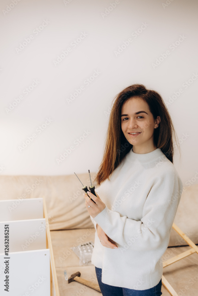 Young Woman Assembling Furniture at Home Holding Screwdrivers Smiling Young Woman Assembling Furniture at Home Holding Screwdrivers Smiling