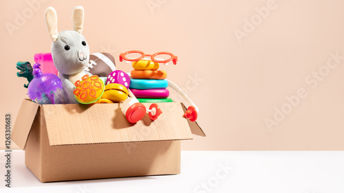 Toys for children in a box ready for donation on beige, copy space. Concept of toys donations, charity for children