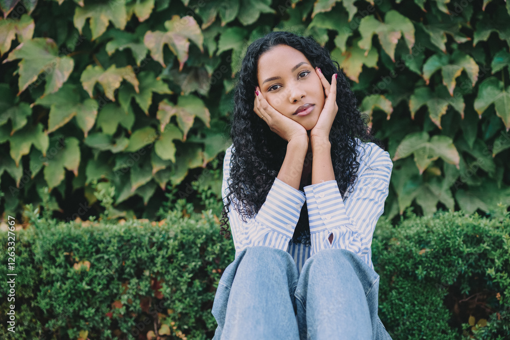 This is a thoughtful young woman dressed in casual attire, surrounded by lush greenery This is a thoughtful young woman dressed in casual attire, surrounded by lush greenery