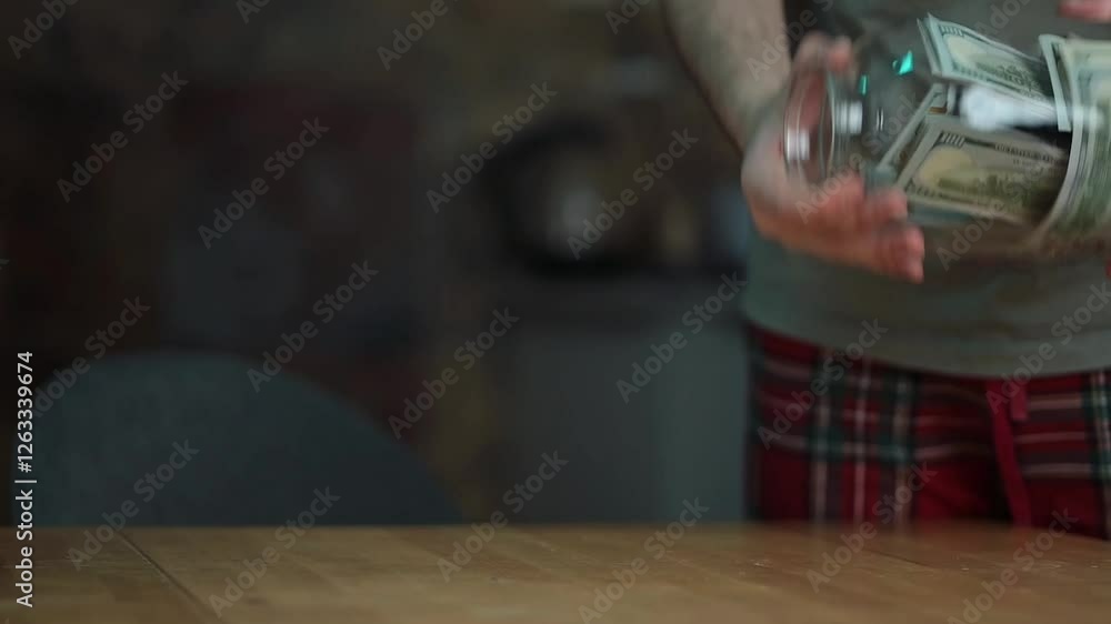 Close-up of a man's hands collecting dollar bills from a glass jar. Close-up of a man's hands collecting dollar bills from a glass jar.