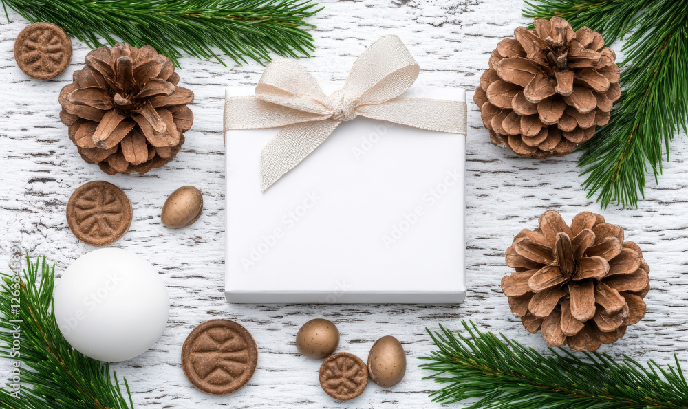 Obraz premium Elegant White Gift Box Surrounded by Natural Pine Cones and Festive Decorations on Rustic Wood Background Ideal for Holidays and Seasonal Celebrations